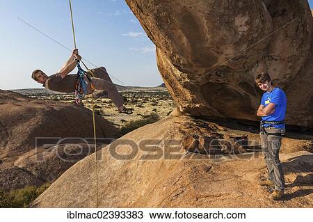 "Young man abseiling from a rock arch, near the Spitzkoppe granite peaks, Damaraland, Namibia, Africa" View Large Photo Image Stock Image - "Young man abseiling from a rock arch, near the Spitzkoppe granite peaks, Damaraland, Namibia, Africa". Fotosearch