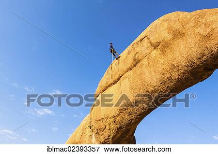 "Young man abseiling from a rock arch, near the Spitzkoppe granite peaks, Damaraland, Namibia, Africa" View Large Photo Image Stock Photo - "Young man abseiling from a rock arch, near the Spitzkoppe granite peaks, Damaraland, Namibia, Africa". Fotosearch