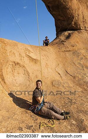"Young man abseiling from a rock arch, hanging upside down, near the Spitzkoppe granite peaks, Damaraland, Namibia, Africa" View Large Photo Image Stock Photo - "Young man abseiling from a rock arch, hanging upside down, near the Spitzkoppe granite peaks, Damaraland, Namibia, Africa". Fotosearch