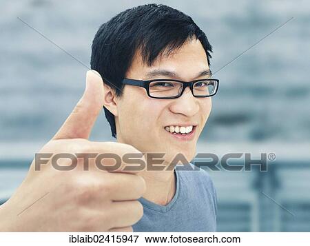 Young man, Asian, student with glasses, smiling, thumbs up gesture, optimistic, positive View Large Photo Image Stock Photo - Young man, Asian, student with glasses, smiling, thumbs up gesture, optimistic, positive. Fotosearch