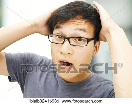 Stock Photography - Young man, Asian, student with glasses, amazed, hands behind his head. Fotosearch