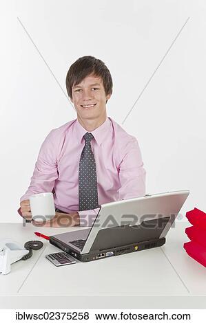 Stock Photo - Young man at his desk in the office with a laptop computer. Fotosearch