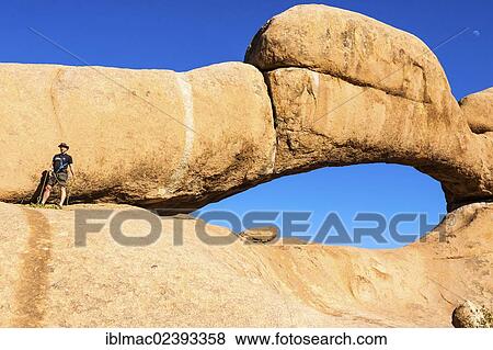 "Young man climbing a rock arch, near the Spitzkoppe granite peaks, Damaraland, Namibia, Africa" View Large Photo Image Stock Photo - "Young man climbing a rock arch, near the Spitzkoppe granite peaks, Damaraland, Namibia, Africa". Fotosearch