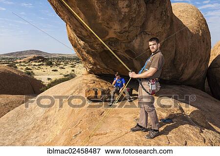 "Young man hanging in a climbing rope, Bogenfels, Spitzkoppe area, Namibia, Africa" View Large Photo Image Stock Photo - "Young man hanging in a climbing rope, Bogenfels, Spitzkoppe area, Namibia, Africa". Fotosearch