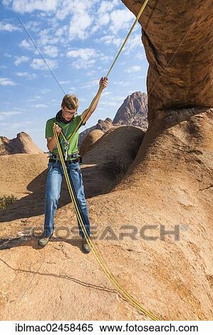 "Young man hanging in a climbing rope, Bogenfels, Spitzkoppe area, Namibia, Africa" View Large Photo Image Stock Photography - "Young man hanging in a climbing rope, Bogenfels, Spitzkoppe area, Namibia, Africa". Fotosearch