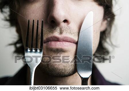 "Young man holding a knife and a fork in front of his face, Germany, Europe" View Large Photo Image Stock Photography - "Young man holding a knife and a fork in front of his face, Germany, Europe". Fotosearch