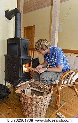 Stock Photo - Young man making a fire in a stove. Fotosearch