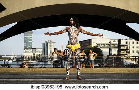 Stock Photography - "Young man painted in Polynesian patterns standing with outstretched arms, Oberbaumbrucke bridge, Berlin, Germany, Europe". Fotosearch