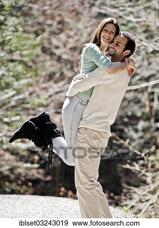 Stock Photo - "Young man picking up a young woman, both smiling, Austria, Europe". Fotosearch