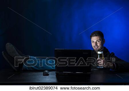 "Young man sitting in the dark in front of his laptop, drinking a beer, symbolic image about computer addiction and alcoholism" View Large Photo Image Picture - "Young man sitting in the dark in front of his laptop, drinking a beer, symbolic image about computer addiction and alcoholism". Fotosearch