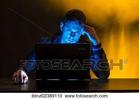 Young man sitting in the dark in front of a laptop View Large Photo Image Stock Image - Young man sitting in the dark in front of a laptop. Fotosearch