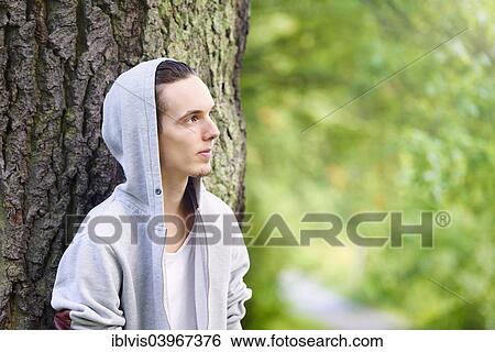 Young man standing by himself and thinking in a forest View Large Photo Image Stock Photograph - Young man standing by himself and thinking in a forest. Fotosearch
