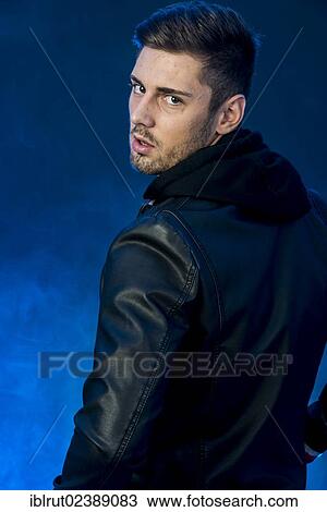 Stock Image - "Young man wearing a black leather jacket, looking over his left shoulder". Fotosearch