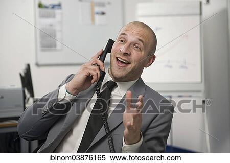 Young man wearing a suit is talking on a phone in the office View Large Photo Image Stock Photography - Young man wearing a suit is talking on a phone in the office. Fotosearch