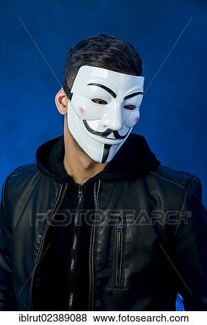 Stock Photo - Young man wearing an anonymous mask and a black leather jacket. Fotosearch