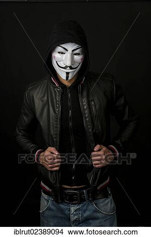 Young man wearing an anonymous mask with a hood and a black leather jacket View Large Photo Image Picture - Young man wearing an anonymous mask with a hood and a black leather jacket. Fotosearch