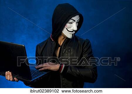 "Young man wearing an anonymous mask with a hood and a black leather jacket, holding a laptop and looking to the side" View Large Photo Image Stock Image - "Young man wearing an anonymous mask with a hood and a black leather jacket, holding a laptop and looking to the side". Fotosearch