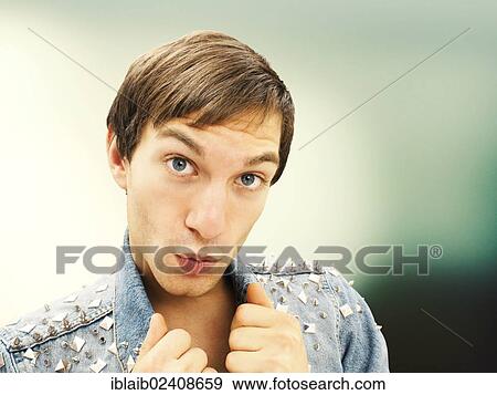 "Young man with an amazed face wearing a studded denim jacket, portrait" View Large Photo Image Stock Photo - "Young man with an amazed face wearing a studded denim jacket, portrait". Fotosearch