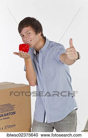 Stock Image - Young man with piggy bank on moving day. Fotosearch