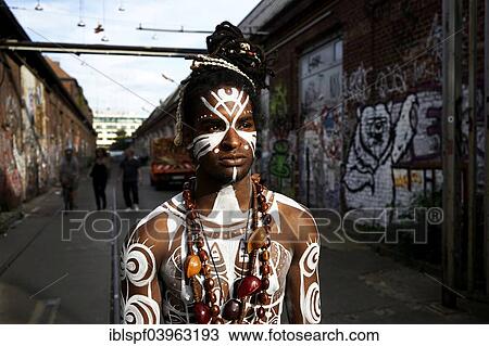 Stock Image - "Young man with Polynesian war paint and jewelry, Berlin, Germany, Europe". Fotosearch