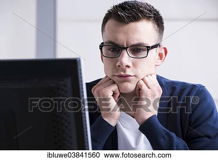 Young man working on a computer View Large Photo Image Stock Image - Young man working on a computer. Fotosearch