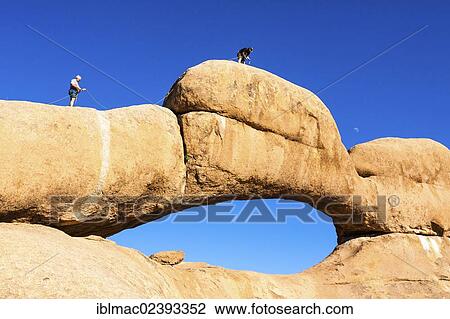 "Young men climbing a rock arch, near the Spitzkoppe granite peaks, Damaraland, Namibia, Africa" View Large Photo Image Stock Image - "Young men climbing a rock arch, near the Spitzkoppe granite peaks, Damaraland, Namibia, Africa". Fotosearch