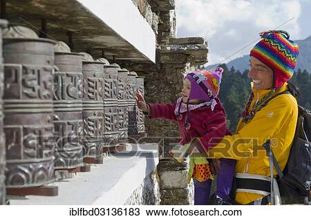 "Young mother wearing yellow cloths and her little child turning prayerwheels, Junbesi, Solukhumbu District, Sagarmatha Zone, Nepal, Asia" View Large Photo Image Stock Image - "Young mother wearing yellow cloths and her little child turning prayerwheels, Junbesi, Solukhumbu District, Sagarmatha Zone, Nepal, Asia". Fotosearch