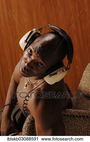 "Young muscular bare-chested man, sitting in an armchair with headphones" View Large Photo Image Stock Image - "Young muscular bare-chested man, sitting in an armchair with headphones". Fotosearch