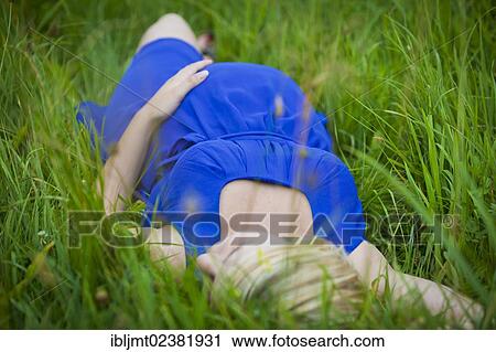 Young pregnant woman lying in the grass and puts her hand on her belly View Large Photo Image Stock Image - Young pregnant woman lying in the grass and puts her hand on her belly. Fotosearch