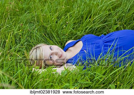 Young pregnant woman lying in the grass and smiling View Large Photo Image Stock Photo - Young pregnant woman lying in the grass and smiling. Fotosearch