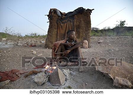 "Young shepherdess from the Himba people sitting at a campfire in front of her hut, Ombombo, Kaokoland, Kunene, Namibia, Africa" View Large Photo Image Stock Photo - "Young shepherdess from the Himba people sitting at a campfire in front of her hut, Ombombo, Kaokoland, Kunene, Namibia, Africa". Fotosearch