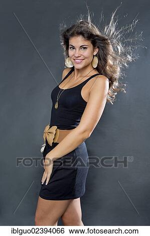 Stock Photograph - Young smiling woman posing in a short black dress. Fotosearch