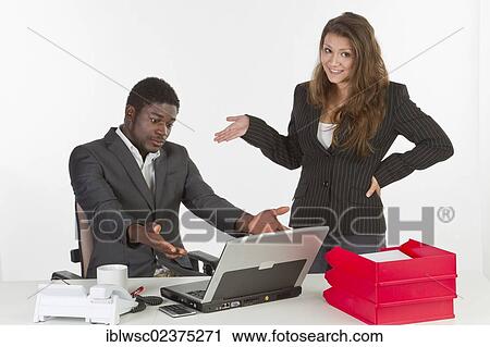 Stock Image - "Young woman and a young man in the office with a laptop computer, having a discussion". Fotosearch