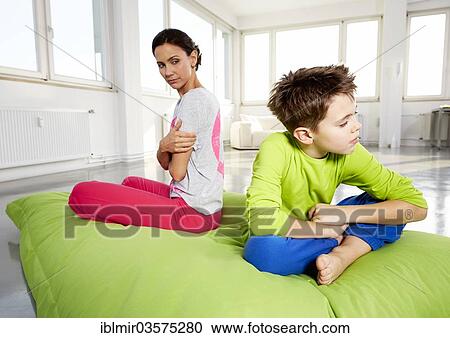 Stock Image - "Young woman and son upset, sitting on a beanbag in a loft, Germany, Europe". Fotosearch