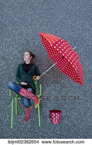 "Young woman appearing to be sitting on a chair holding a dotted umbrella, taken from above" View Large Photo Image Picture - "Young woman appearing to be sitting on a chair holding a dotted umbrella, taken from above". Fotosearch