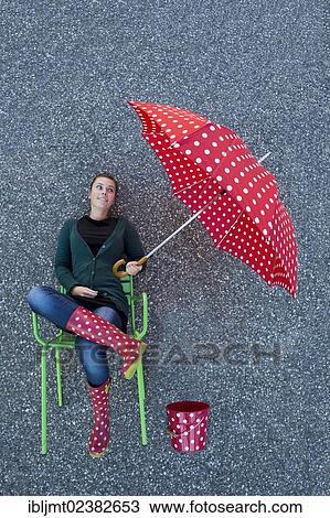 "Young woman appearing to be sitting on a chair holding a dotted umbrella, taken from above" View Large Photo Image Stock Image - "Young woman appearing to be sitting on a chair holding a dotted umbrella, taken from above". Fotosearch