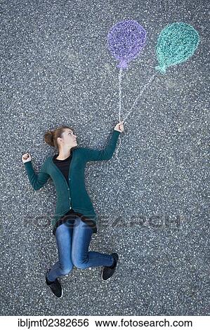 "Young woman appearing to be suspended from two painted balloons, taken from above" View Large Photo Image Stock Photograph - "Young woman appearing to be suspended from two painted balloons, taken from above". Fotosearch