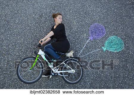 "Young woman appearing to cycle on a children's bicycle, painted balloons tied to the rack, taken from above" View Large Photo Image Stock Photo - "Young woman appearing to cycle on a children's bicycle, painted balloons tied to the rack, taken from above". Fotosearch