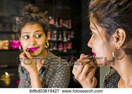 Stock Photo - "Young woman applying lipstick, in a make-up shop, Mumbai, Maharashtra, India, Asia". Fotosearch
