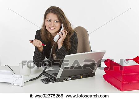 "Young woman at her desk with a laptop computer, making phone call" View Large Photo Image Stock Photograph - "Young woman at her desk with a laptop computer, making phone call". Fotosearch