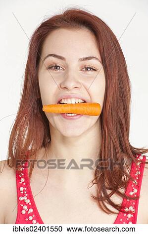 Young woman biting on an organic carrot View Large Photo Image Stock Image - Young woman biting on an organic carrot. Fotosearch