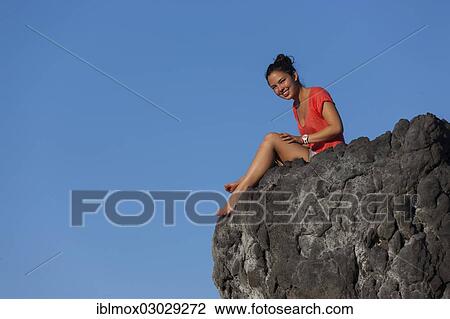 "Young woman, ca. 19, sitting on a rock in front of the blue sky, Sukadana, Tukad Batang, Bali, Indonesia, Asia" View Large Photo Image Stock Image - "Young woman, ca. 19, sitting on a rock in front of the blue sky, Sukadana, Tukad Batang, Bali, Indonesia, Asia". Fotosearch