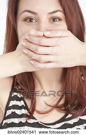 Stock Image - Young woman covering mouth with hands. Fotosearch