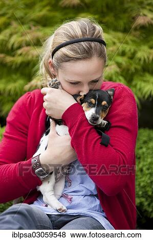 Stock Photo - "Young woman cuddling a Jack Russell puppy, Austria, Europe". Fotosearch