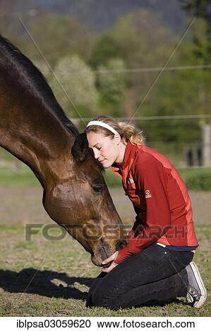 Stock Image - "Young woman cuddling an Austrian Warmblood, bay horse". Fotosearch