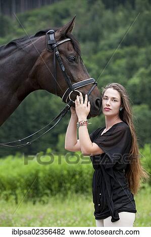 Stock Image - "Young woman cuddling with a Hanoverian horse, bay, North Tyrol, Austria, Europe". Fotosearch