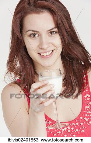 Stock Image - Young woman drinking milk from a wine glass. Fotosearch