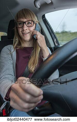 Young woman driving a car while talking on her cell phone View Large Photo Image Stock Photo - Young woman driving a car while talking on her cell phone. Fotosearch
