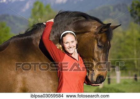 "Young woman embracing an Austrian Warmblood, bay horse" View Large Photo Image Picture - "Young woman embracing an Austrian Warmblood, bay horse". Fotosearch