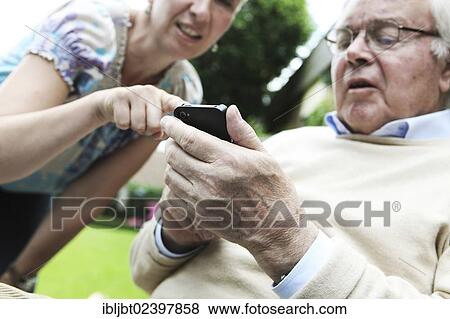Young woman explaining to a senior citizen how to use a smartphone View Large Photo Image Stock Photo - Young woman explaining to a senior citizen how to use a smartphone. Fotosearch